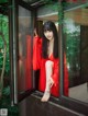 A woman in a red robe sitting on a window sill.