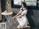 A woman in a white dress sitting on the floor.