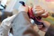 A person tying a tie on a mannequin's hand.