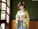 A woman in a yellow and blue kimono standing in front of a window.