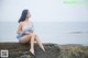 A woman sitting on a rock by the ocean.