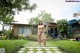 A woman standing in front of a house in a garden.