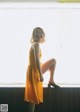 A woman in a yellow dress sitting on a window sill.