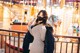 A woman wearing a face mask standing in front of a carousel.