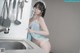 A woman in a blue and white lingerie standing in a kitchen.