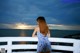 A woman in a blue and white dress looking out over the ocean.