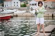 A woman standing on a dock holding a towel.