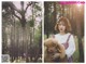 A woman holding a teddy bear in a forest.