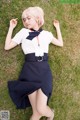 A woman in a white shirt and black skirt laying on the grass.